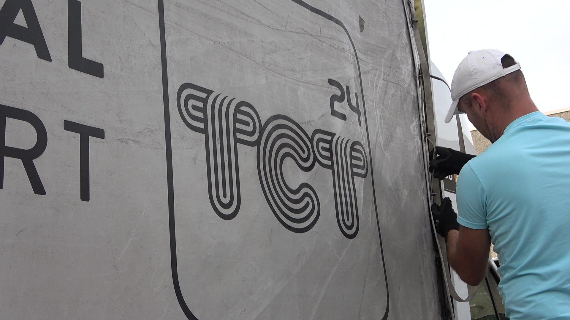 Autista TCT24 fissa il telone accanto al logo
